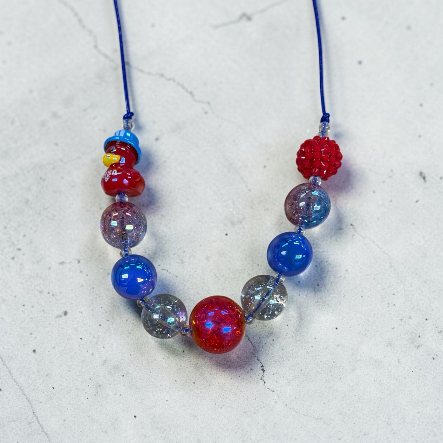 Mloved Designs red, white, and blue beaded statement necklace with novelty duck charm on a blue cord.