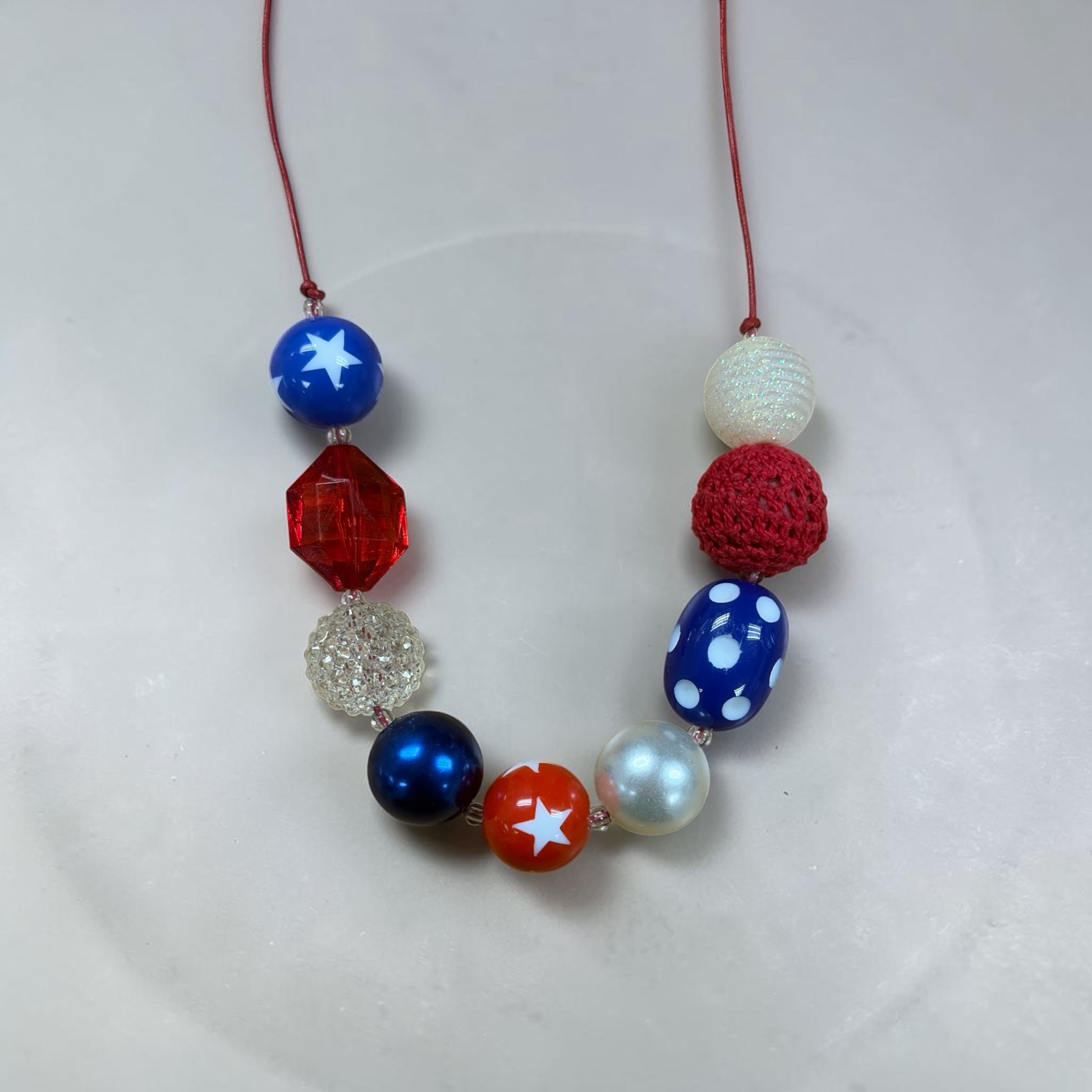 Mloved Designs patriotic beaded statement necklace with red, white, and blue star, pearl, and crochet textured beads.